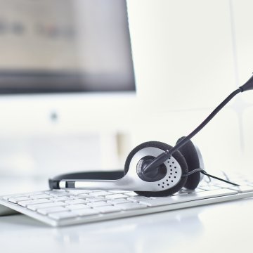 voip services tips headset on computer keyboard monitor in the background